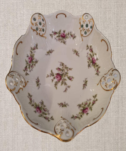 Din colecția Rosenthal Classic Rose acest vas de porțelan ivory este o piesă fermecătoare, decorată cu trandafiri și prevăzută cu 5 inserții din filigran. Realizat de renumita companie germană Rosenthal în anii 1980, vasul cu picioare este o capodoperă de rafinament și eleganță.